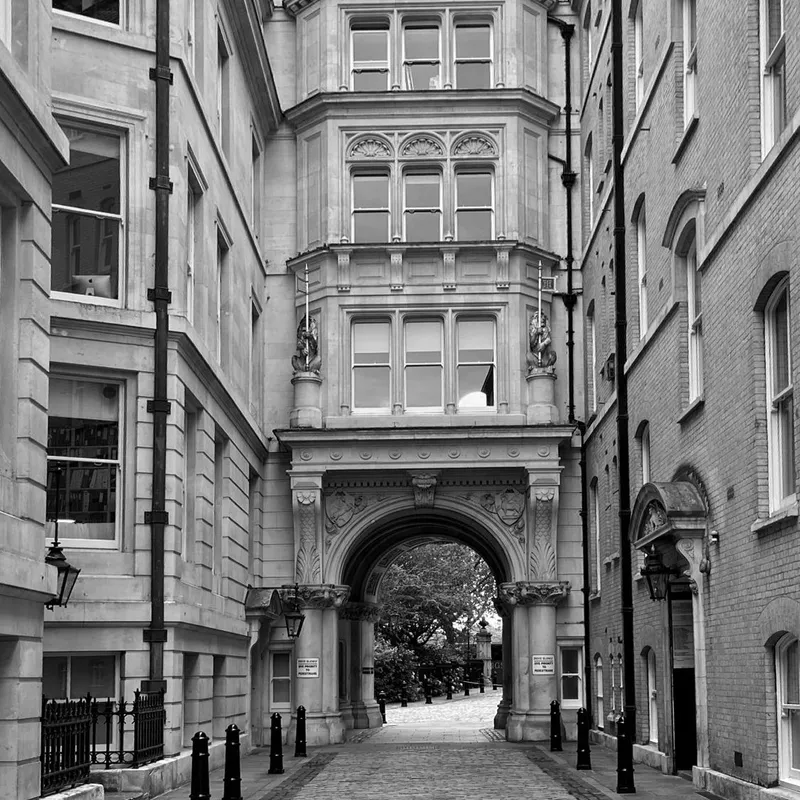 A cobbled lane in London leading through a stone archway